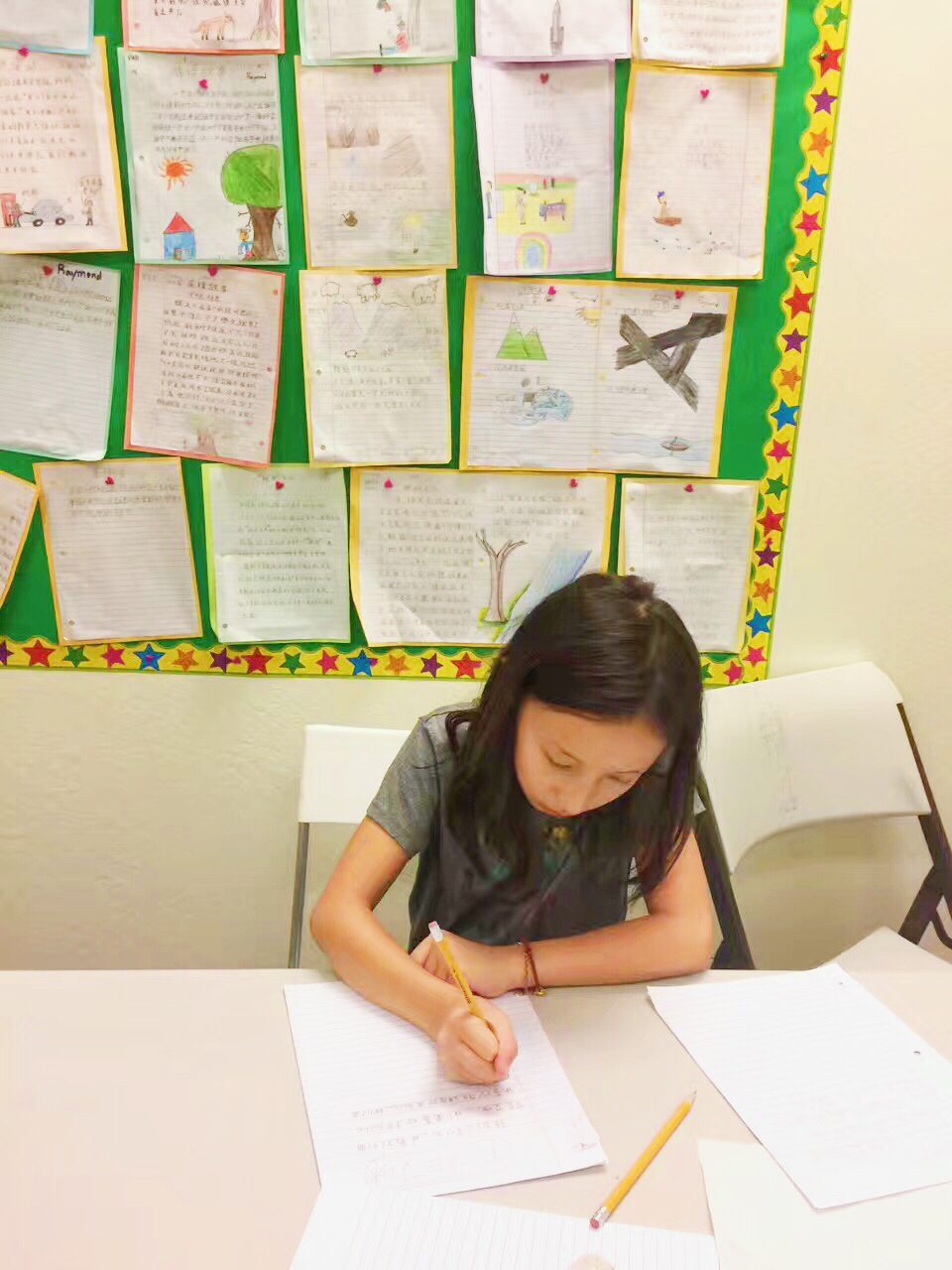 Children practicing Chinese characters with brushes in a bright classroom