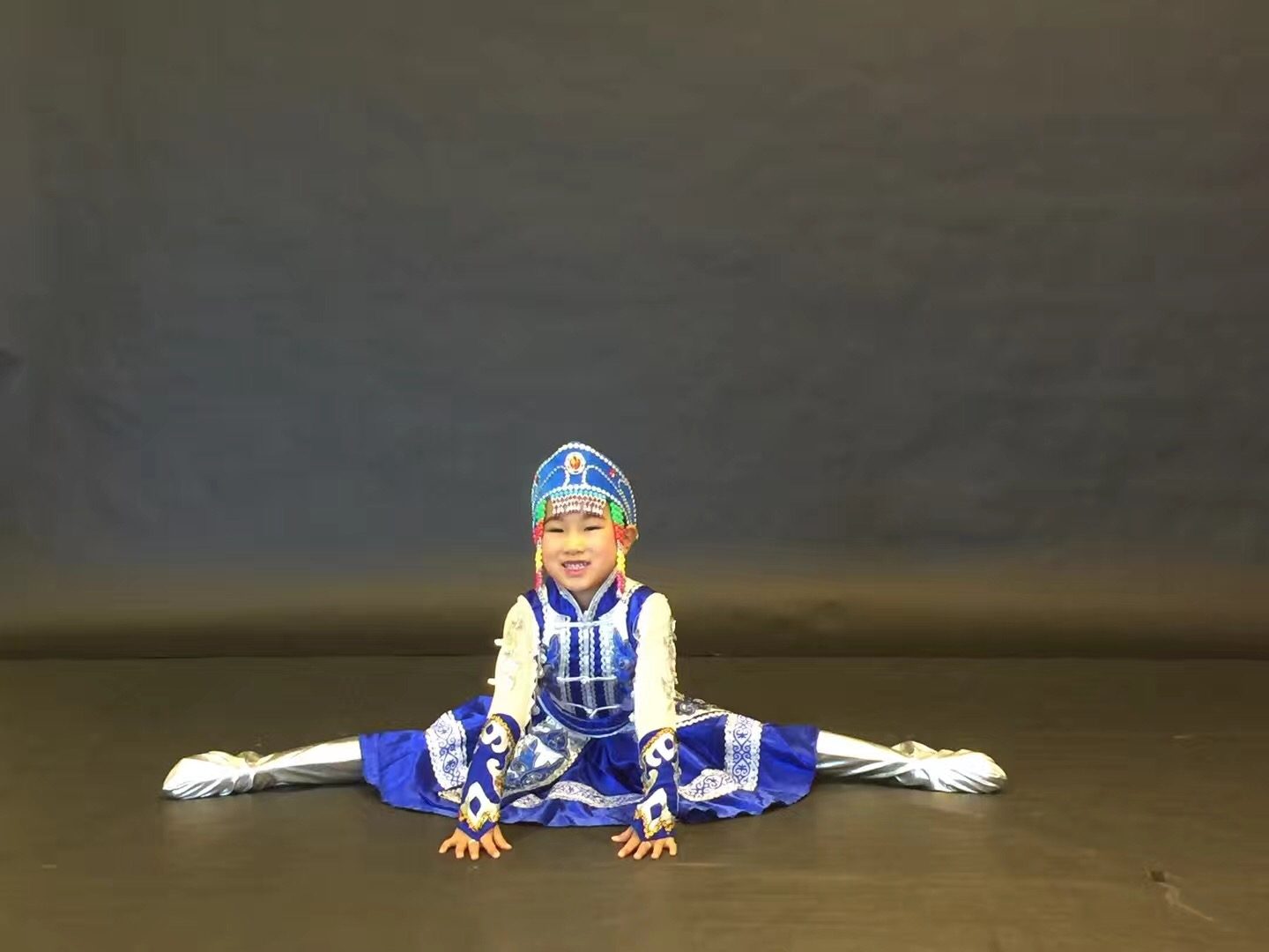 A young dancer holding a split pose on stage